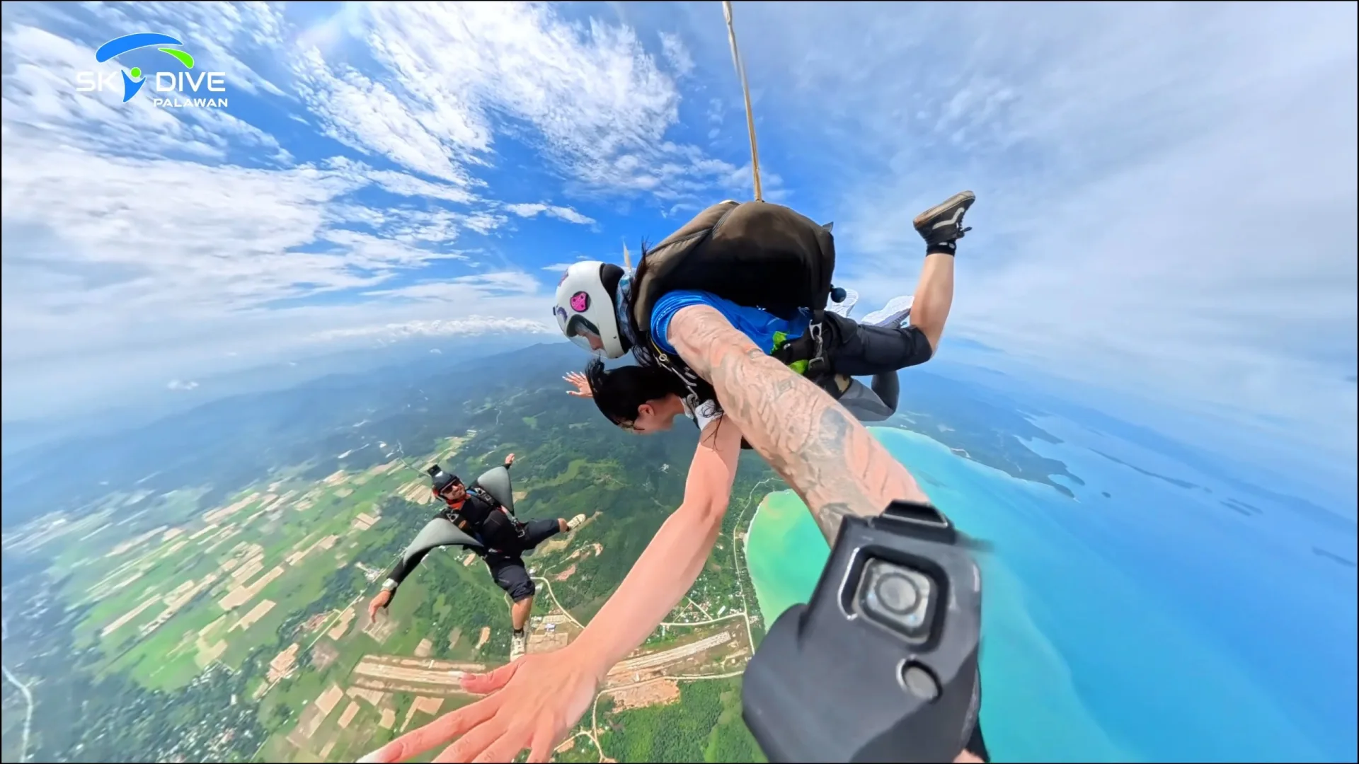 Tandem skydivers in freefall over San Vicente, Palawan, filmed from outside by a professional camera flyer