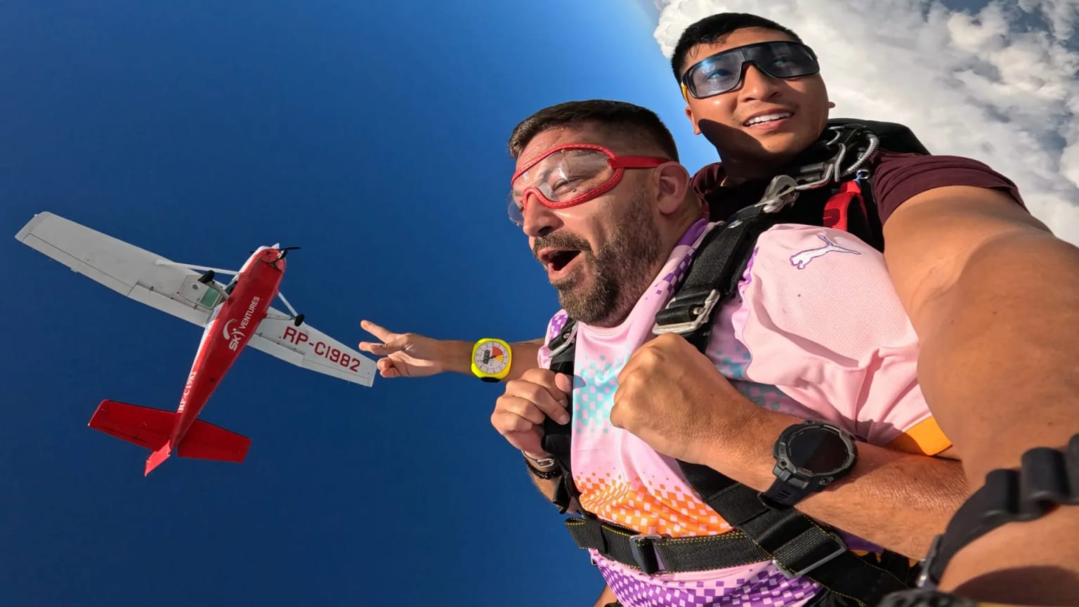 Tandem jumper in goggles harnessed to a USPA-certified instructor in freefall over Palawan