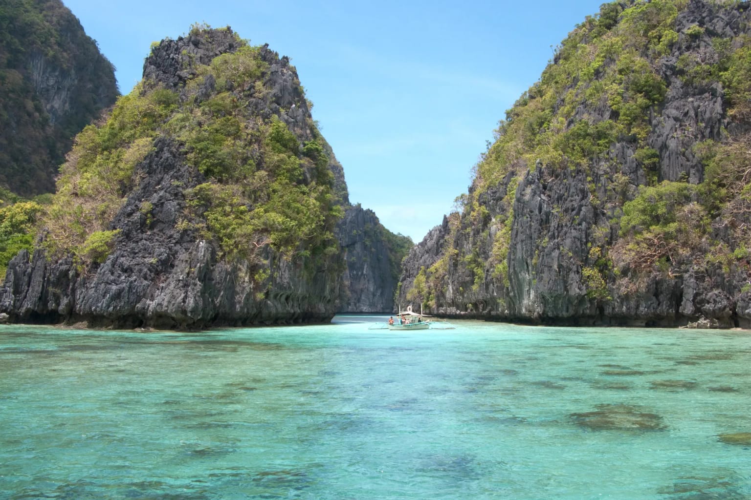 Outrigger boat between limestone karst islands in the turquoise lagoon of Bacuit Bay, El Nido